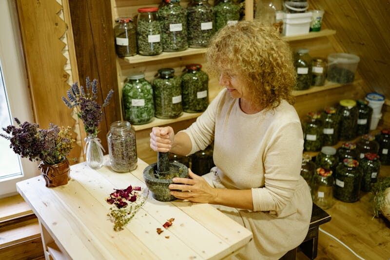 Herbalist preparing dried medicinal herbs and natural remedies in a traditional workshop